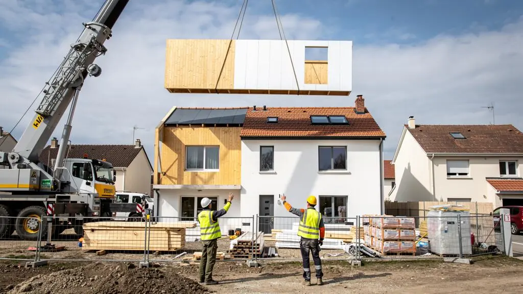 Grue de chantier installant des modules préfabriqués sur le toit d'une maison en cours de surélévation